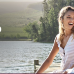 a woman sitting on a dock by a lake